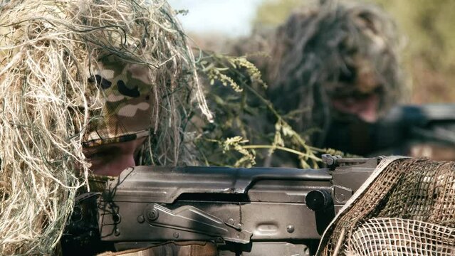Snipers in an ambush in the grass, disguised as terrain on an anti-terrorist operation with sniper rifles, shooting at the enemy. Footage of military operations. Soldiers in full gear. Cinematic shot