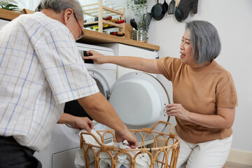 senior woman and her husband doing laundry together with washing machine at home