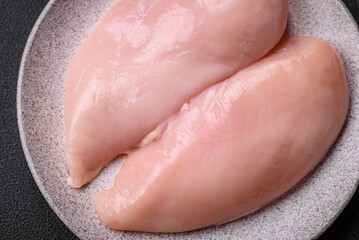 Fototapeta premium Fresh chicken fillet on a dark concrete table with spices and herbs