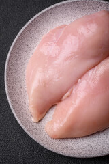 Fresh chicken fillet on a dark concrete table with spices and herbs