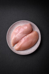 Fresh chicken fillet on a dark concrete table with spices and herbs
