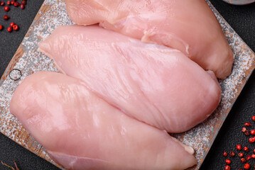 Fresh chicken fillet on a dark concrete table with spices and herbs