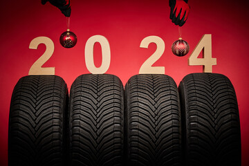 Winter car tires, big wheels service and hands of mechanics with christmas tree ball on new year...