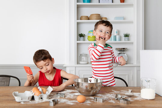 Happy brothers with messy face baking chocolate cake together