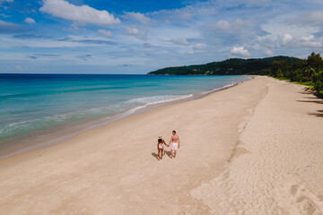 A couple of men and women relaxing on a white tropical beach with palm trees in Phuket Thailand