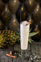 alcoholic cocktail of white color on a board with pineapple vertical photo