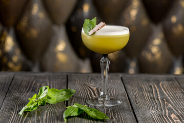 green cocktail on a wooden board with basil leaves