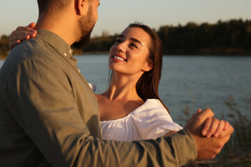 Beautiful couple dancing near river at sunset