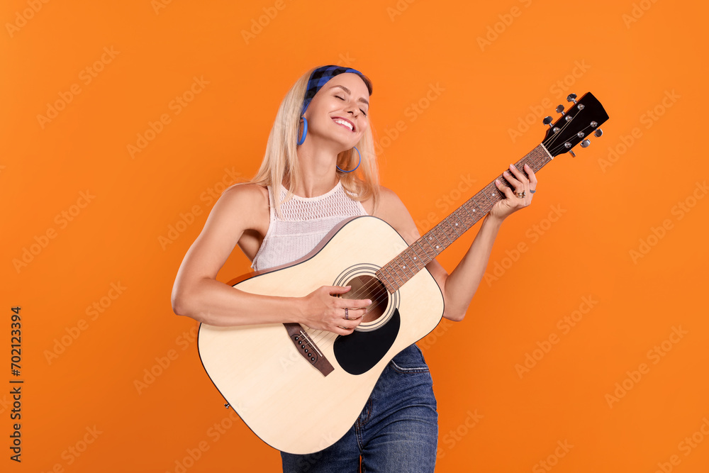 Sticker Happy hippie woman playing guitar on orange background