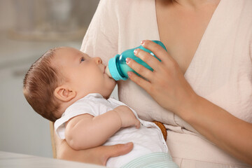 Obraz na płótnie Canvas Mother feeding her cute child with infant formula indoors