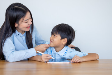 Teacher teaching kid boy student using digital tablet computer. Mother and her son use tablet...
