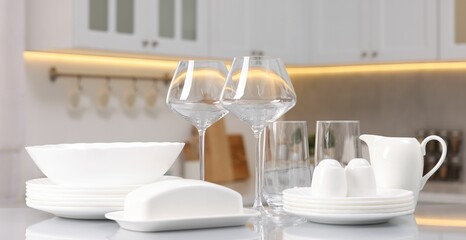 Fototapeta na wymiar Set of clean dishware and glasses on table in kitchen