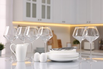 Set of clean dishware, glasses and cutlery on table in kitchen