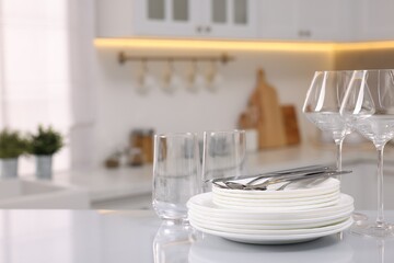 Set of clean dishware, glasses and cutlery on table in kitchen, space for text