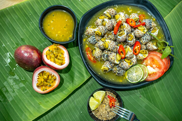 Steamed Spotted Babylon Blanching (Fresh Sea Babylonia Areolata Shell Boiled) served with passion fruit sauce goodtasty decorated with spices side view