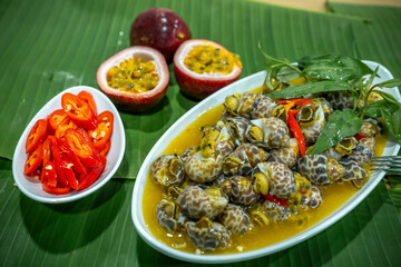 Steamed Spotted Babylon Blanching (Fresh Sea Babylonia Areolata Shell Boiled) served with passion fruit sauce goodtasty decorated with spices side view
