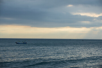 Obraz premium Silhouette of a fishing boat on sea before sunset.