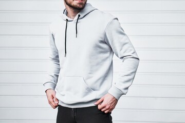 A mock-up template of a white hoodie worn by a man. A design concept for print and branding. A...