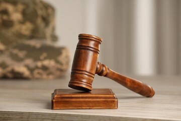 Law concept. Gavel and military uniform on wooden table, closeup