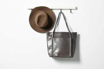 Brown hat and bag hanging on hook rack on white wall