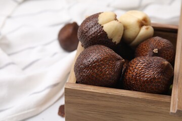 Wooden crate with fresh salak fruits on table, closeup. Space for text