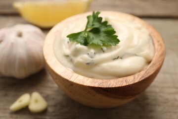 Tasty sauce with garlic and parsley on wooden table, closeup