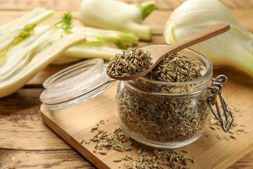 Jar and spoon with fennel seeds on wooden table, closeup
