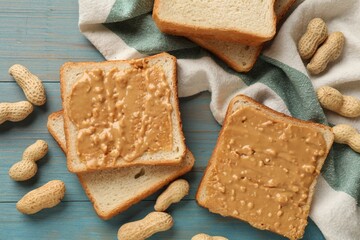 Delicious toasts with peanut butter and nuts on light blue wooden table, flat lay