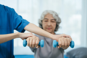 senior woman doing exercise at clinic with physiotherapist. help of a personal trainer during a rehabilitation session.