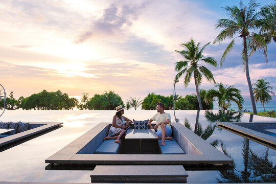 couple watching the sunset in an infinity pool on a luxury vacation in Thailand