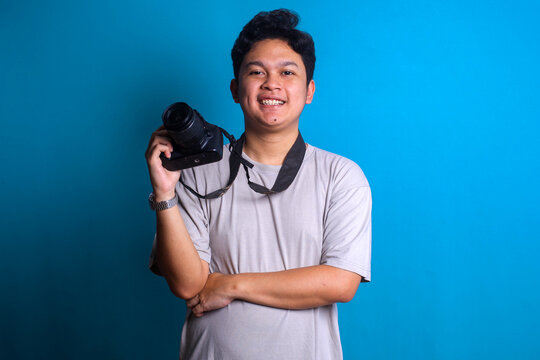 Excited young photographer standing confidently and smiling while holding camera