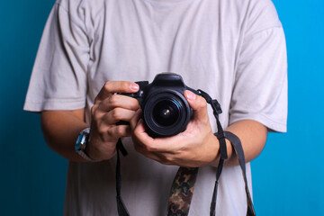 Digital single-lens reflex camera in hands. Male hands hold the camera close-up and adjust lens.