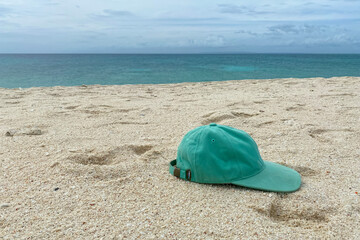 Forgotten cap on a sandy beach against the blue sea
