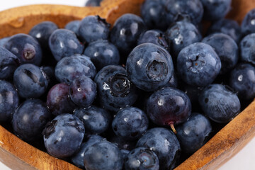 Blueberries in a wooden plate on a white background.