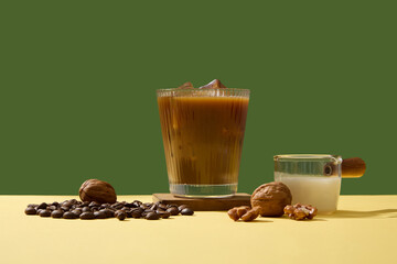 Minimal scene for advertising drink product with a delicious cup of coffee, beans, walnuts and milk on green background. Caffeine in coffee helps focus, energize and increase alertness