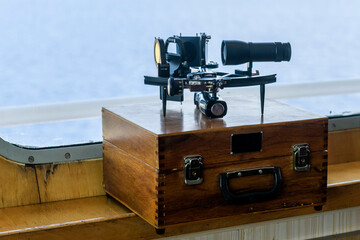 Nautical black sextant placed on wooden box in navigational bridge. Navigational equipment. Celestial navigation.