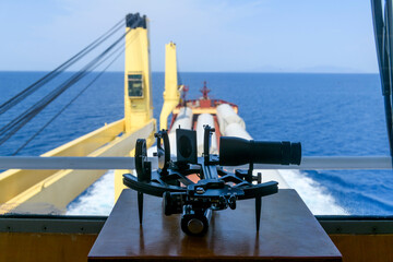 Nautical black sextant placed on wooden box in navigational bridge. Navigational equipment....