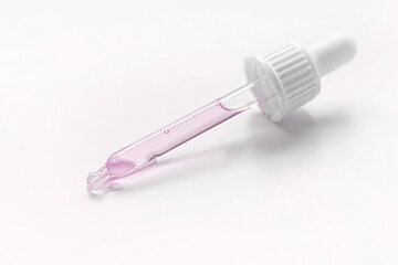 Cosmetic pipette with pink gel, serum, serum on a light background.