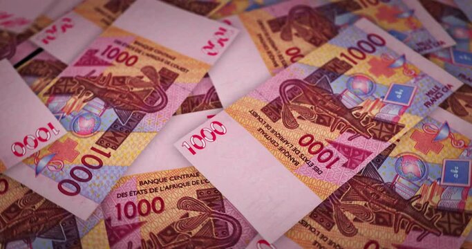 West African CFA Franc growing pile of money. XOF banknotes loop rotaring. Seamless and looped background concept of finance, economy crisis, inflation and business.