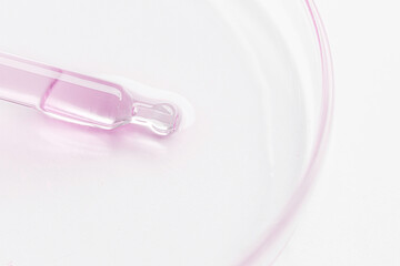 Petri dish. Cosmetic pipette with pink gel, serum, serum on a light background.
