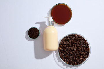 Scene for advertising organic product. A pump bottle with petri dishes filled with coffee beans on white background. Coffee extract in hair care products helps keep hair strong and shiny