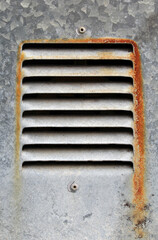 Close up of a rusty vent with a textured background