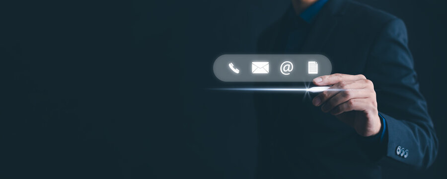 Communication and Contact us or Customer support hotline people connect. Businessman Hand using a laptop and touching on virtual screen contact icons, email and address, live chat with internet wifi.