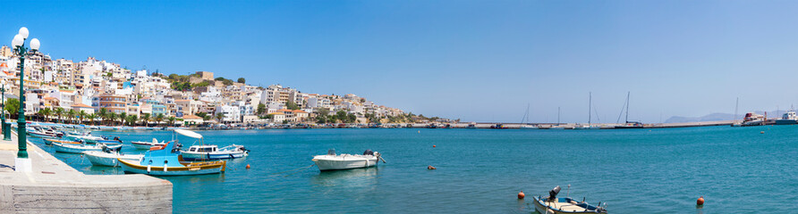 Fototapeta na wymiar Sea bay with moored boats. Promenade in Mediterranean town Sitia, Crete