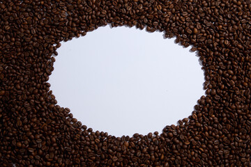 Top view of brown roasted coffee beans decorated on white background and create an empty space in the middle for display product or design text. Creative background for advertising