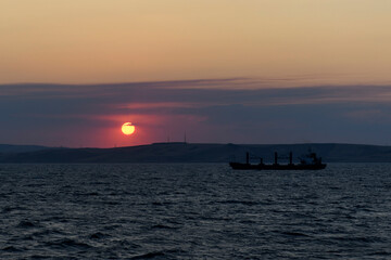 Fototapeta premium Cargo vessel at sea. Bulk carrier. Dry cargo ship at sunset.