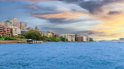Fototapeta premium North Sydney water front residential property Circular Quay and Sydney Rocks Ferry on Sydney Harbour NSW Australia. Lovely colours of the Sky and water