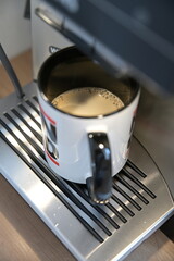 Coffee mug with coffee crema under the outlet of a fully automatic coffee machine