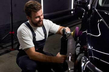 Side view on caucasian man auto mechanic worker polishing car at automobile repair and renew service station shop by power buffer machine. Copy Space