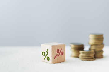 Flipped down percentage to up percentage icon on wooden cube block  with blurred coin including copy space for investment, interest, tax, fund concept